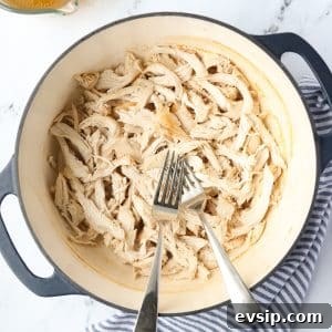 Juicy Shredded Chicken Made in a Dutch Oven 11 A Dutch Oven with two forks and shredded chicken.