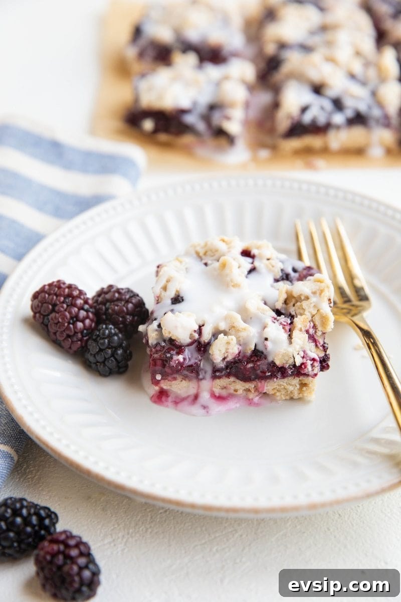 Gluten-Free Vegan Blackberry Pie Bars — 5 Ingredients 2 White plate with a blackberry crumb bar and fresh blackberries to the side and a gold fork.