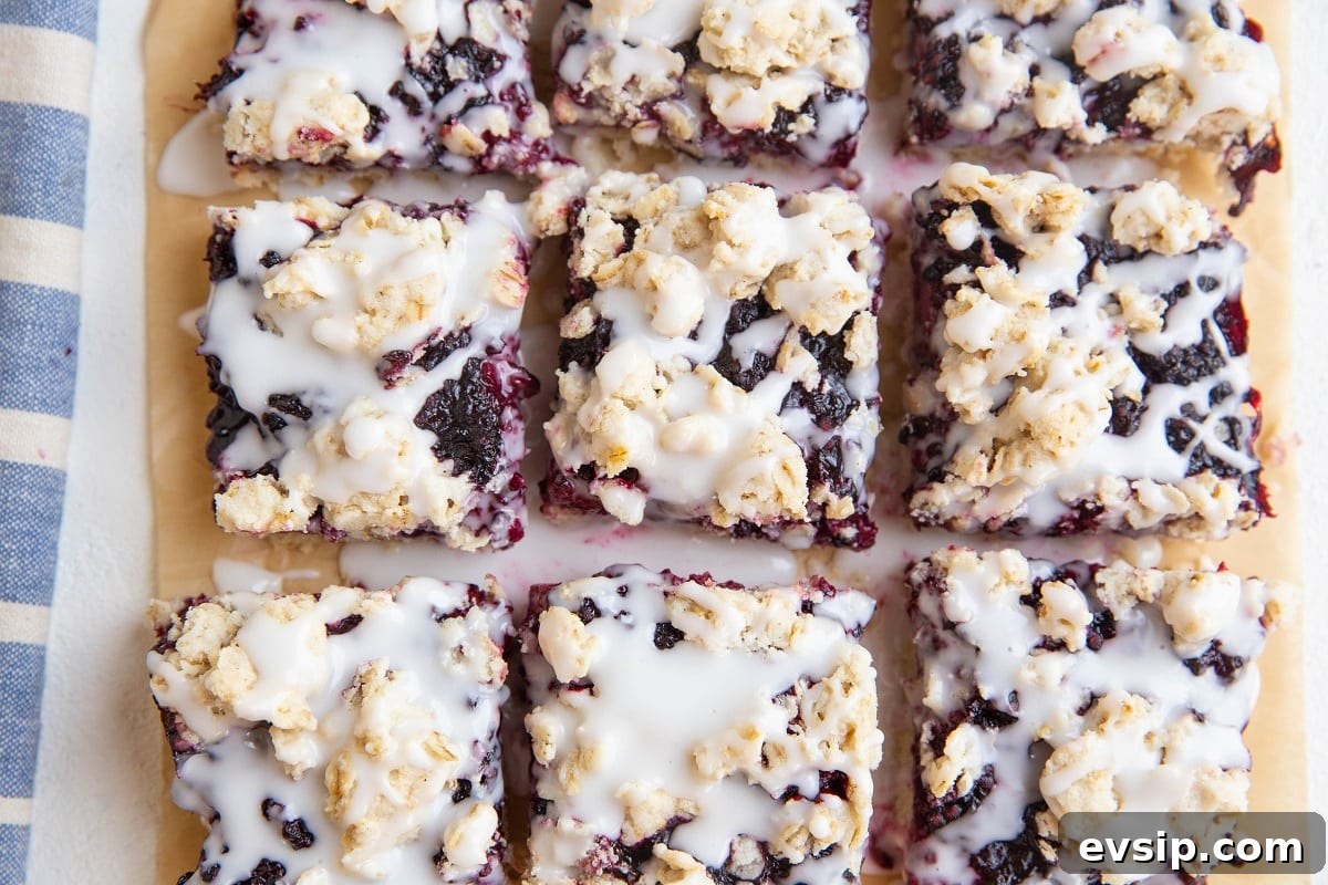 Gluten-Free Vegan Blackberry Pie Bars — 5 Ingredients 11 horizontal photo of blackberry crumb bars on parchment paper drizzled with glaze
