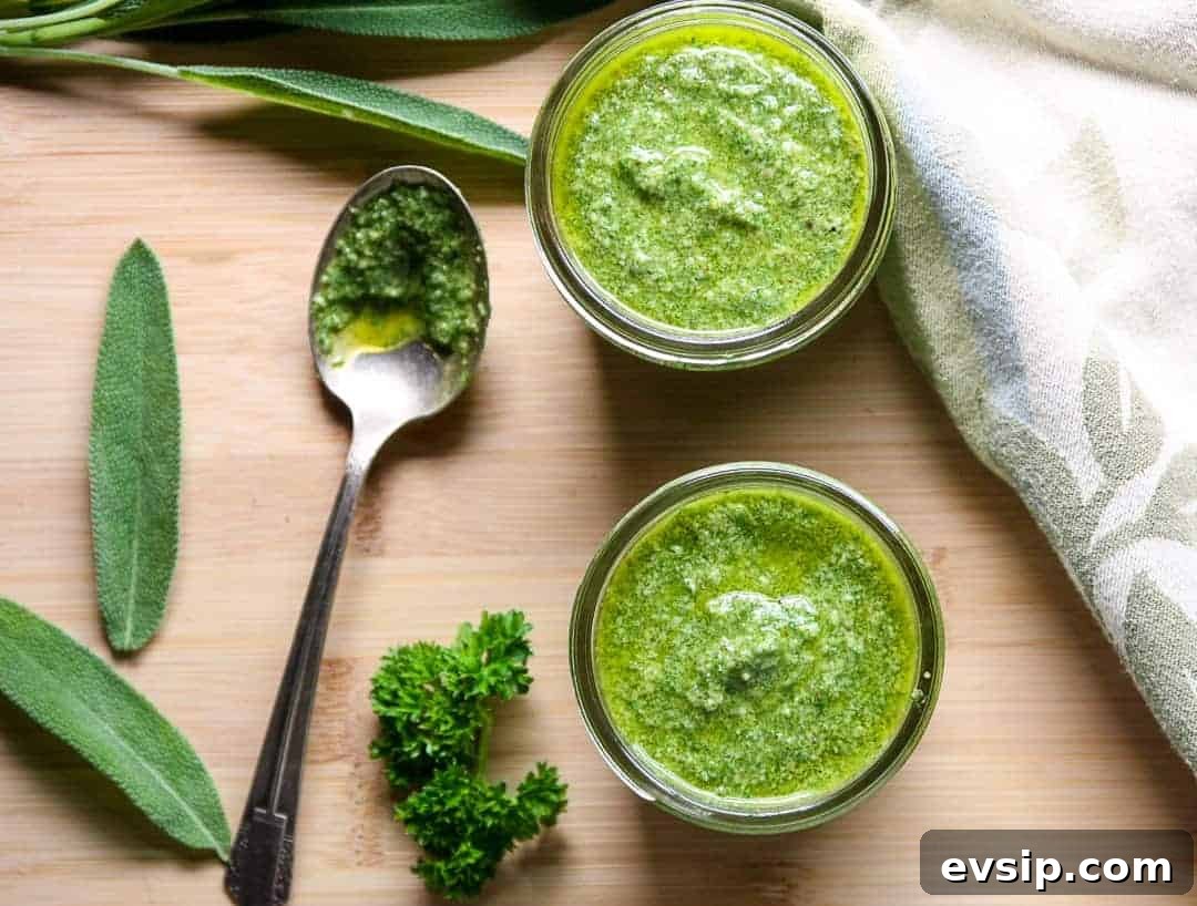 Two half pint jars of walnut sage pesto with sage and parsley leaves