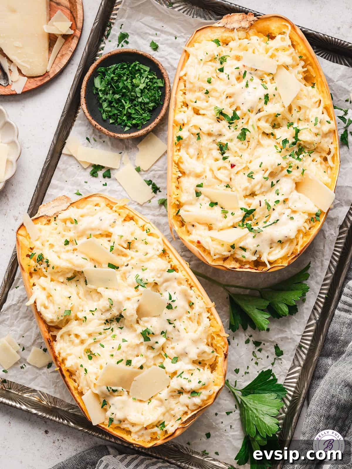 2 halves of spaghetti squash alfredo on baking sheet, garnished with parsley