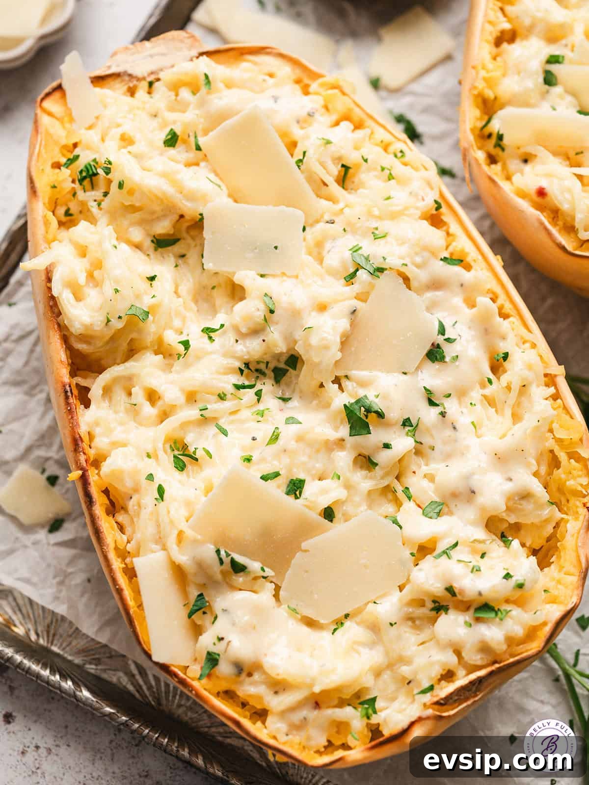 half of a roasted spaghetti squash mixed with alfredo sauce, garnished with parsley