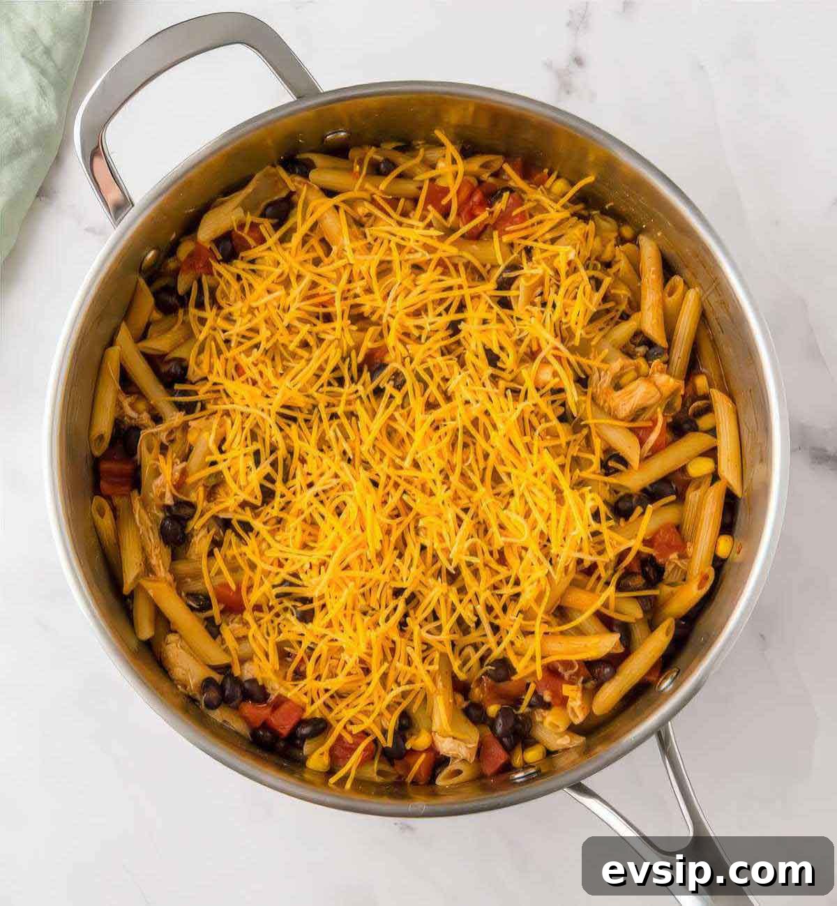 30-Minute One-Pot Chicken Enchilada Pasta Recipe 6 Shredded cheddar cheese sprinkled over cooked chicken enchilada pasta in a skillet