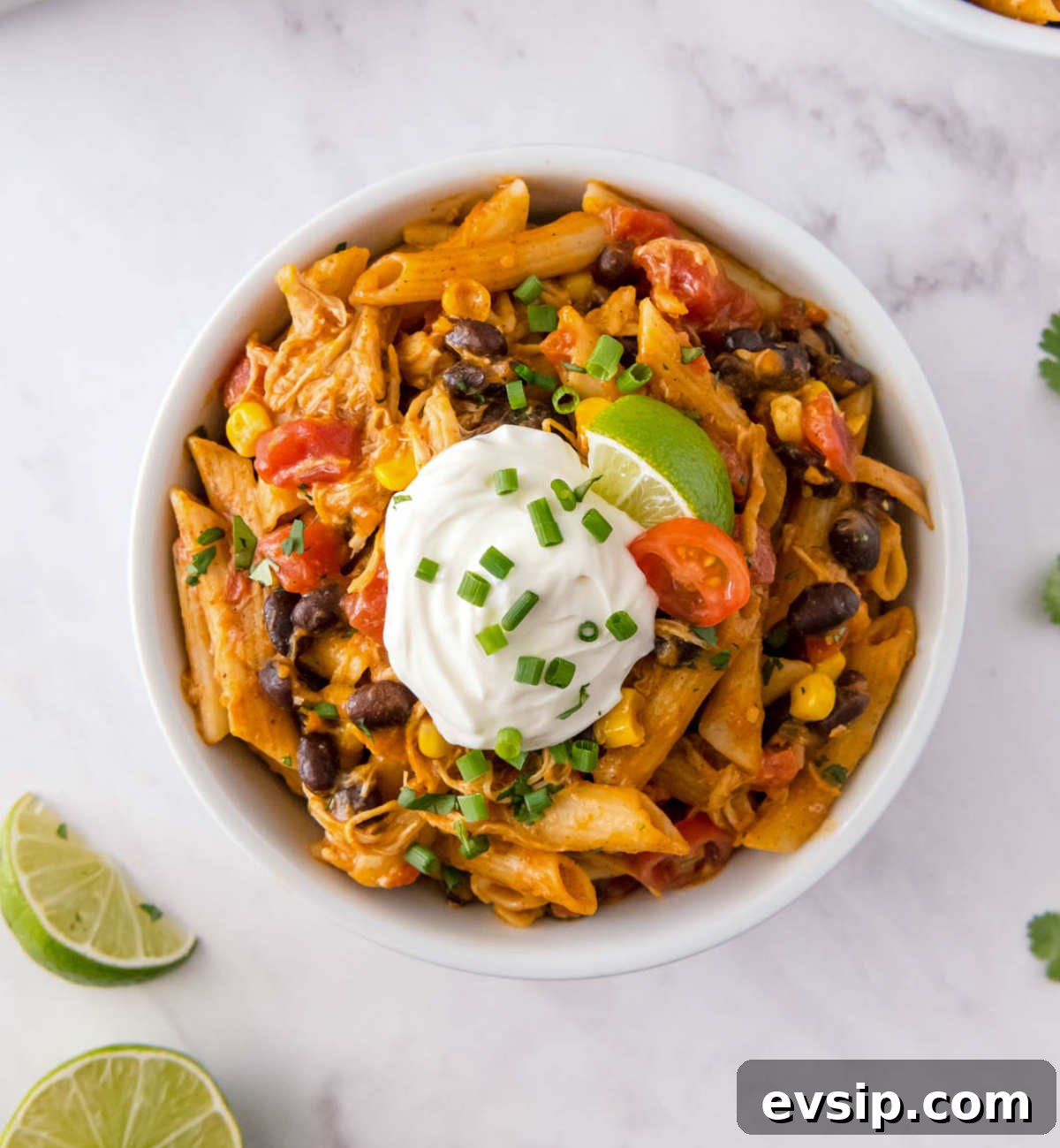 30-Minute One-Pot Chicken Enchilada Pasta Recipe 7 Close up of chicken enchilada pasta topped with sour cream, lime and green onions