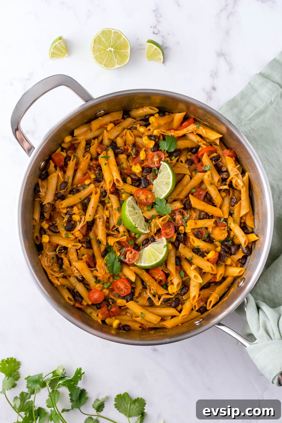 30-Minute One-Pot Chicken Enchilada Pasta Recipe 8 One pot chicken enchilada pasta in a skillet with black beans, corn, tomatoes and lime wedges
