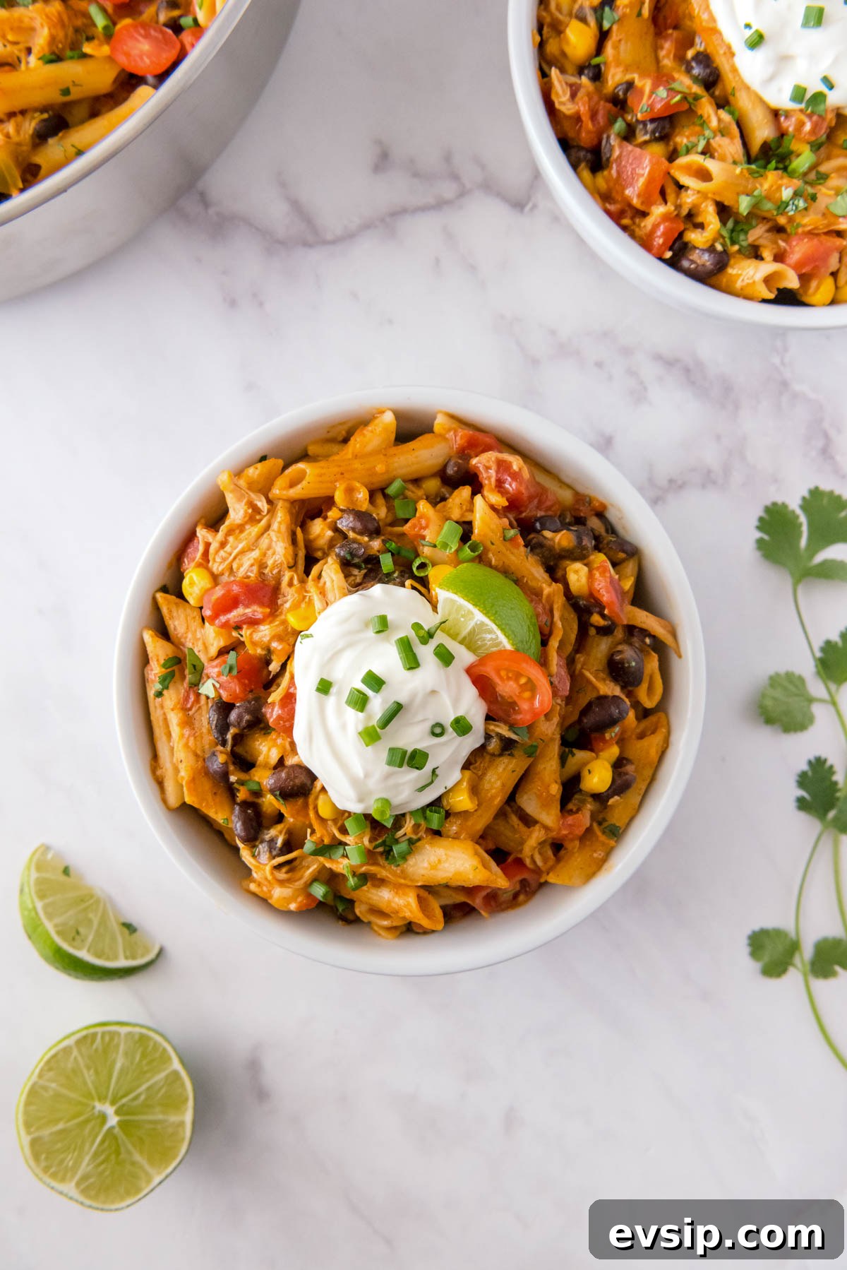 30-Minute One-Pot Chicken Enchilada Pasta Recipe 9 Chicken enchilada pasta served in a bowl topped with sour cream, lime wedge, black beans, corn and fresh cilantro
