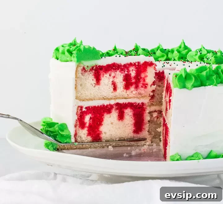 Christmas Poke Cake Recipe: Festive Holiday Dessert 2 Christmas poke cake on a cake stand with a cake server lifting a slice away