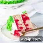 Christmas Poke Cake Recipe: Festive Holiday Dessert 9 slice of Christmas cake on a plate with a fork taking a bite out of it