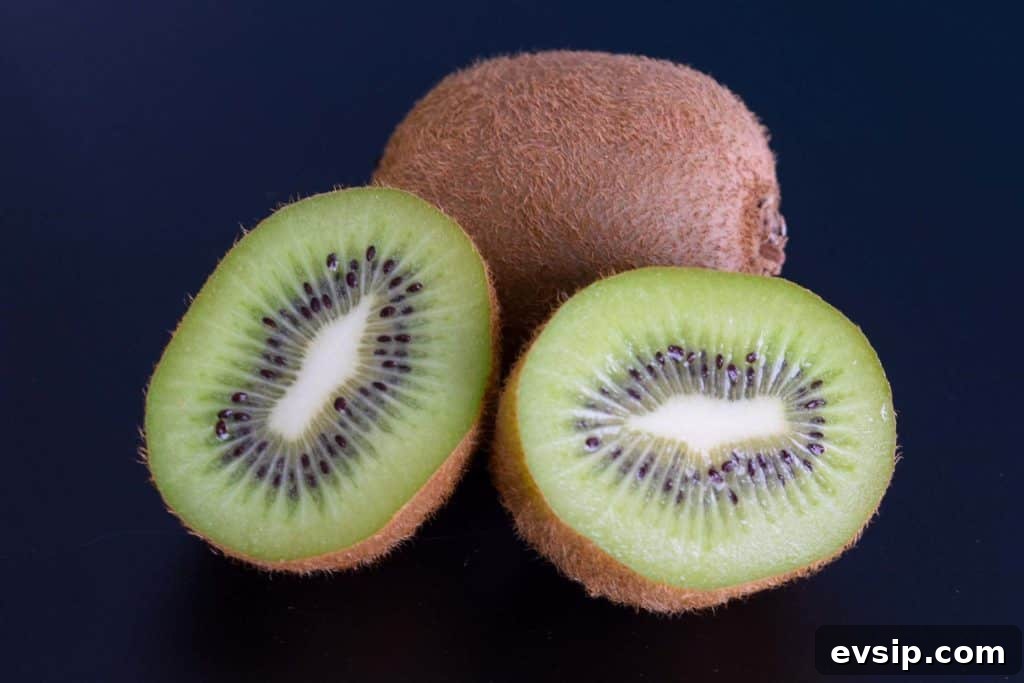 one sliced kiwi and one whole kiwi on black background 