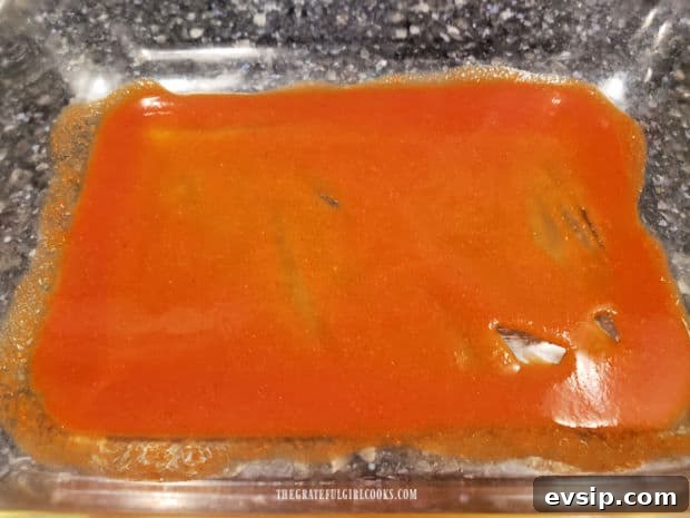 Air Fryer Cheese Enchiladas - The Grateful Girl Cooks! A small amount of enchilada sauce is spread on the bottom of the baking dish.