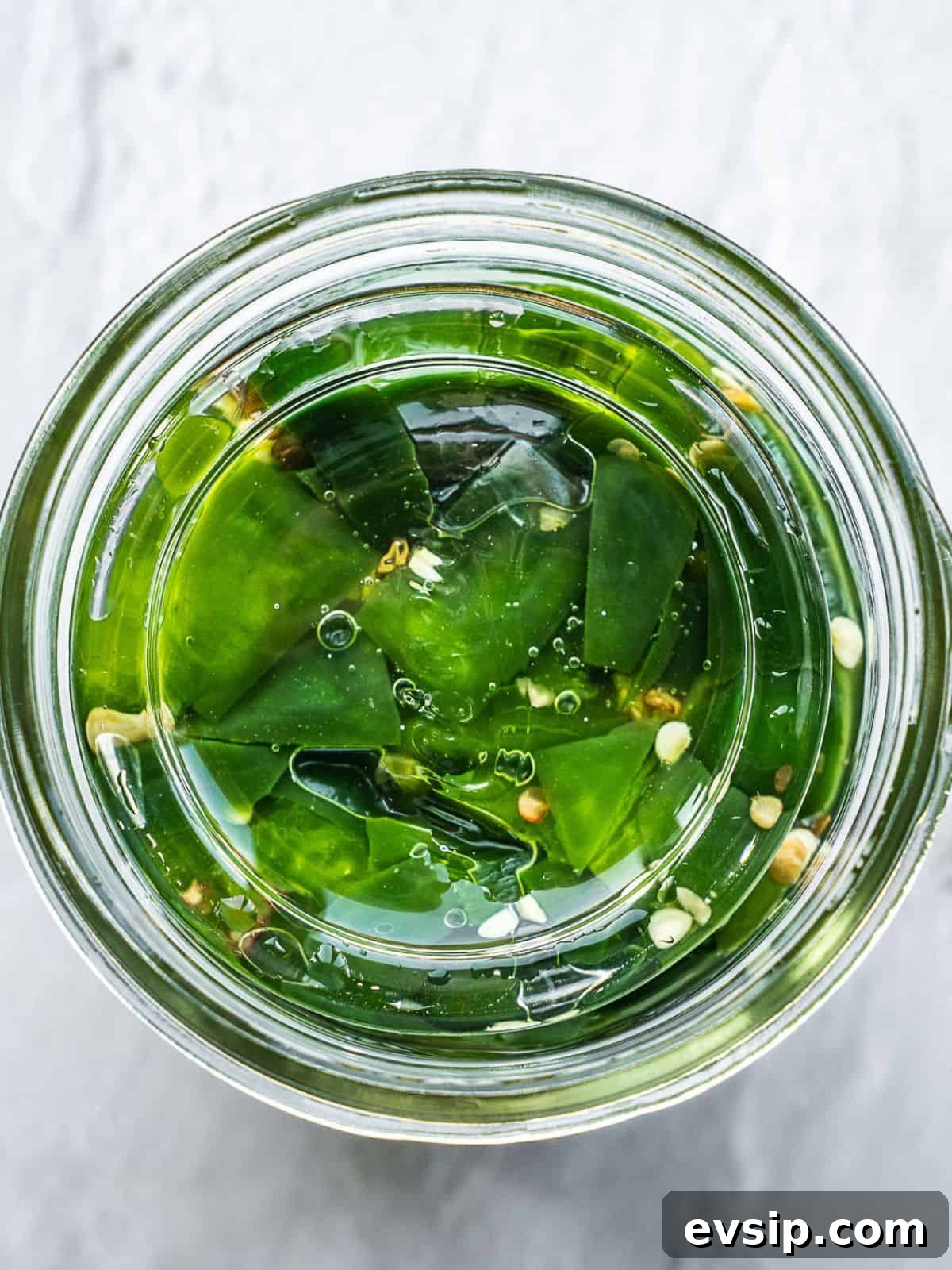 A round glass weight holding down the hot peppers inside a mason jar. 
