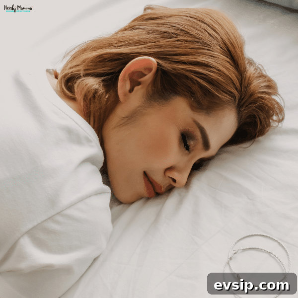 A woman sleeps on her side with her face resting on a pillow, with makeup on, highlighting how this habit may affect skin health.