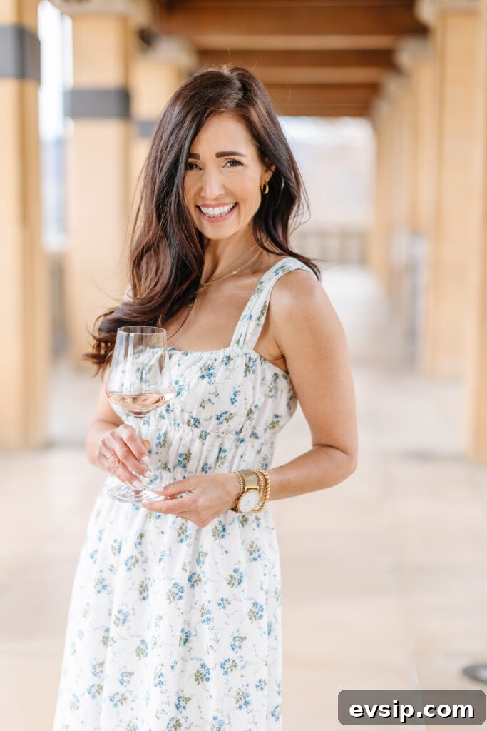 Tori holding a glass of wine in her French Floral midi dress from The Fraîche x PRIV Summer Collection