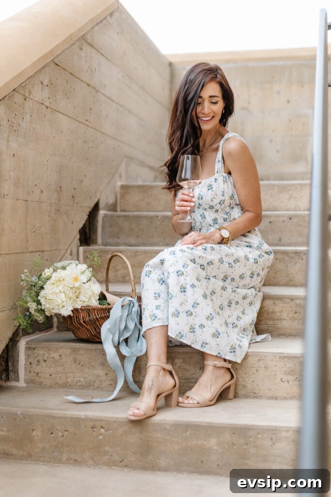 Tori sitting on steps in her blue and white floral dress with a glass of wine from The Fraîche x PRIV Summer Collection