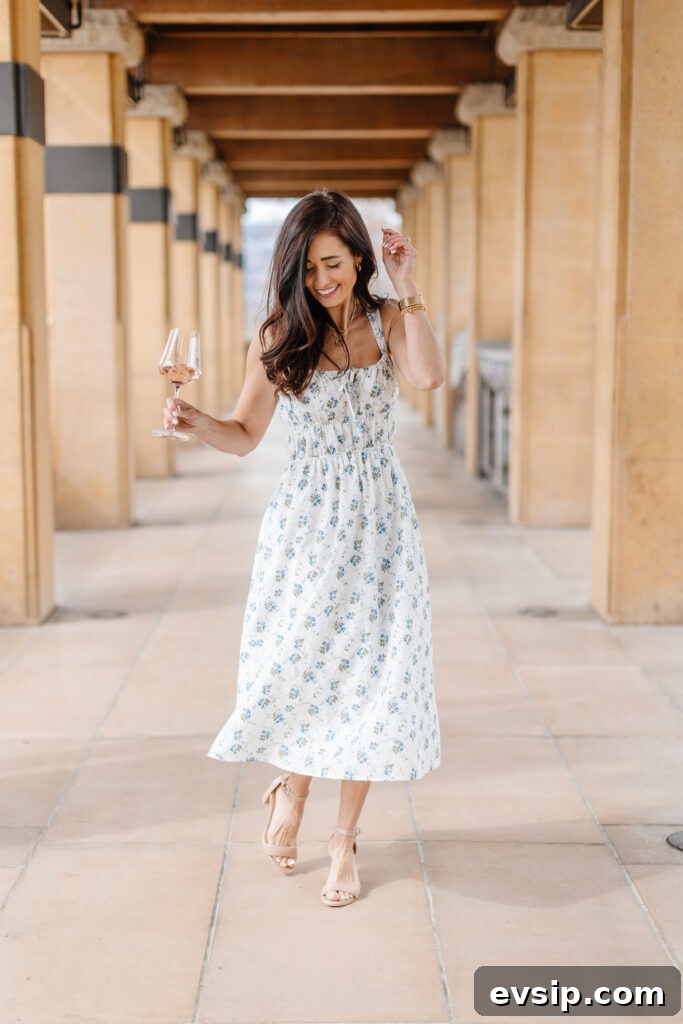 Tori dancing in her blue and white floral dress with a glass of wine from The Fraîche x PRIV Summer Collection