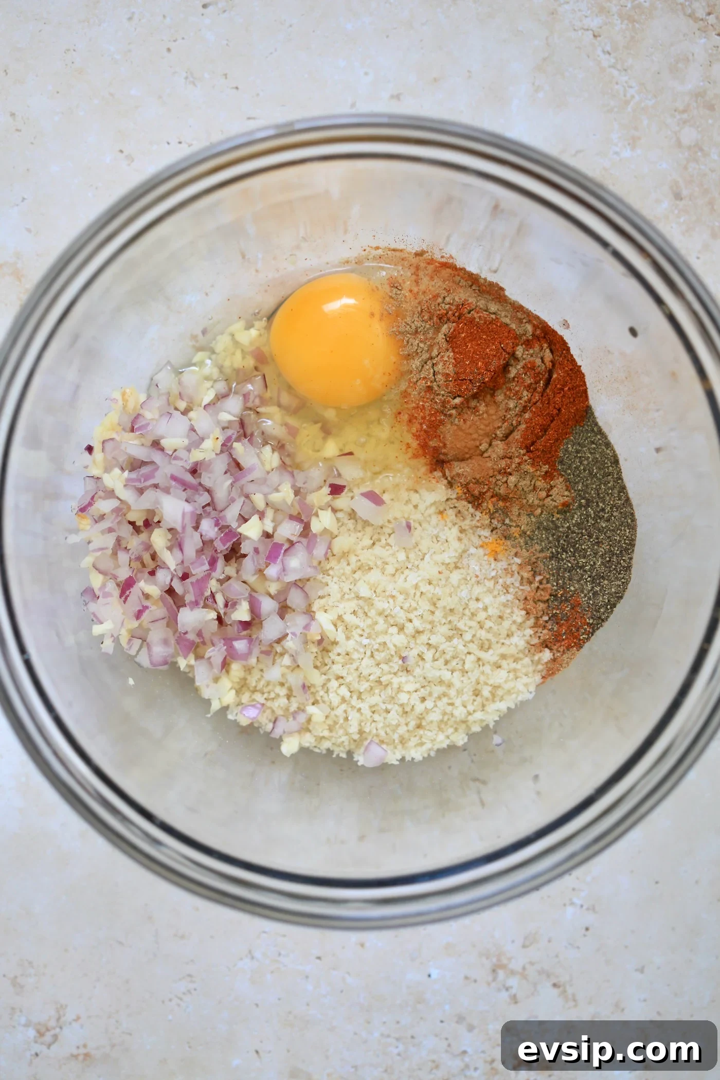 egg, onion, breadcrumbs, and meat in bowl.