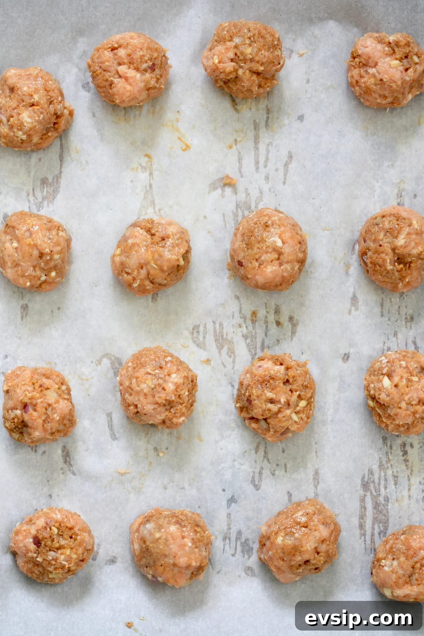 raw meatballs on lined baking sheet.