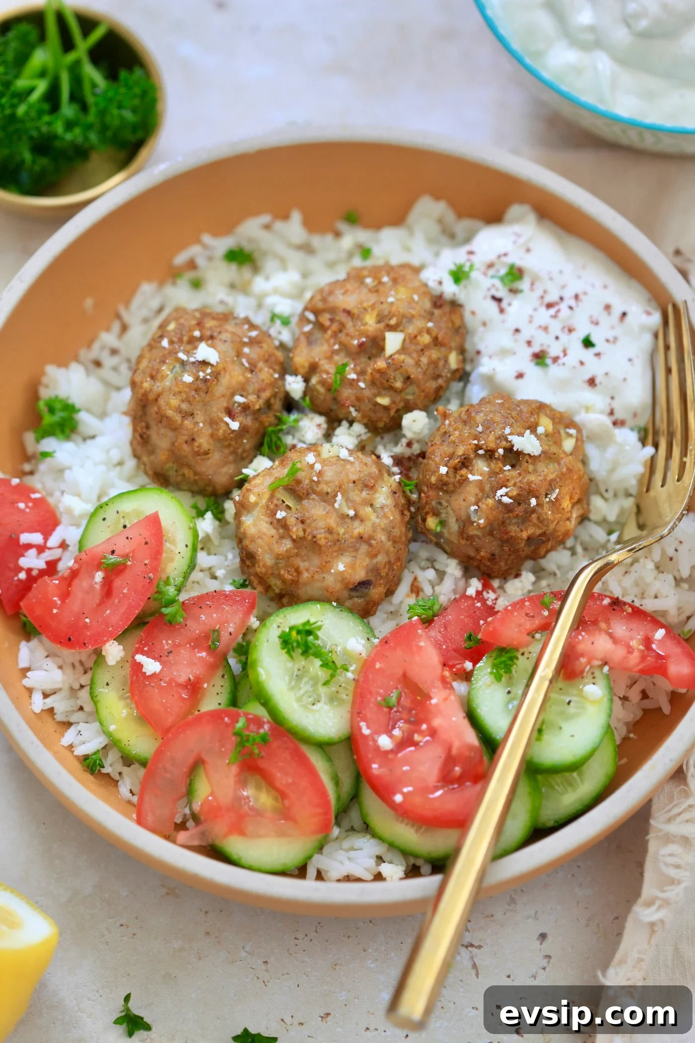 bowl with meatballs, rice and veggies and gold spoon.