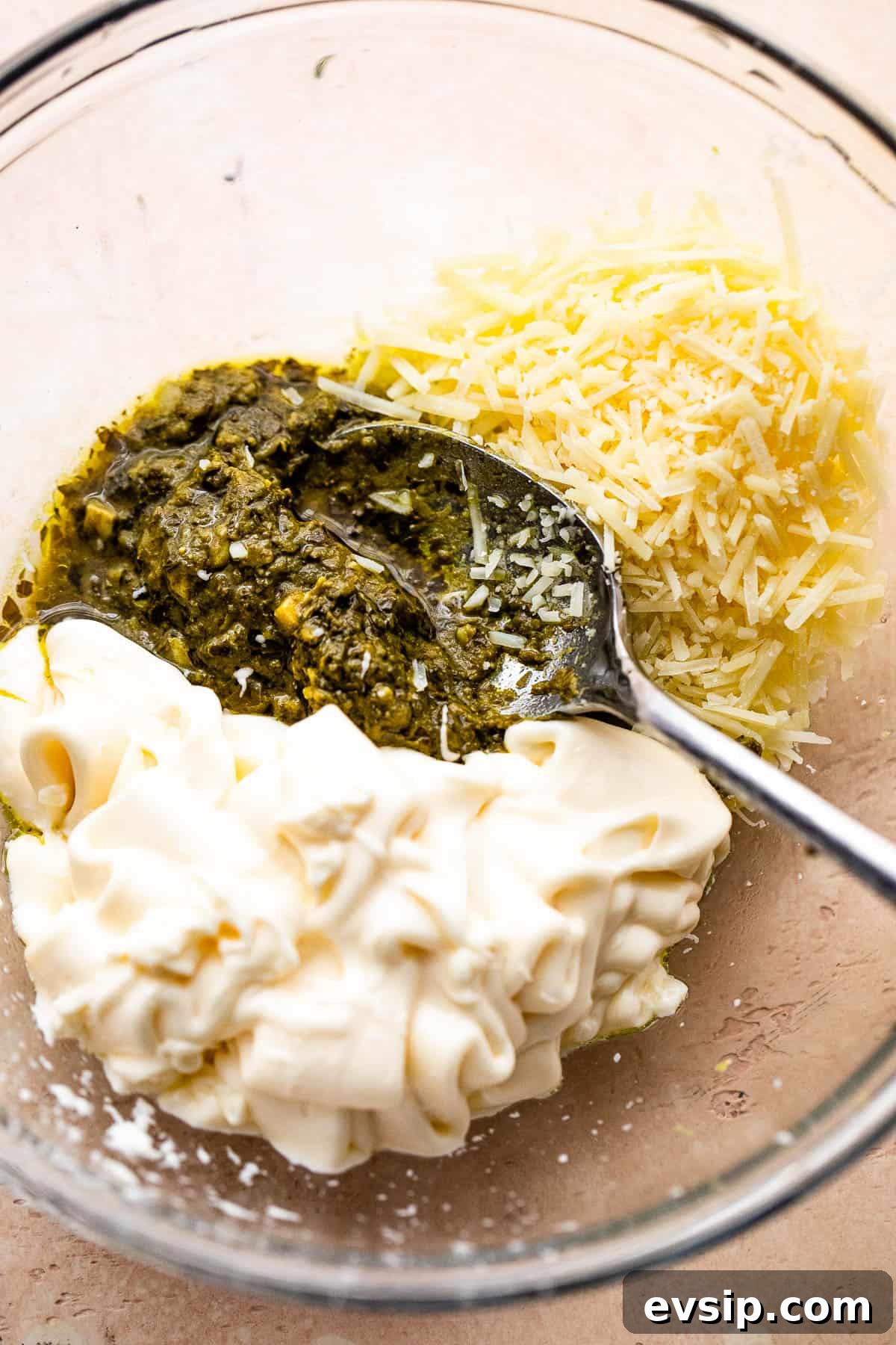 mixing together basil pesto, mayonnaise, and parmesan cheese