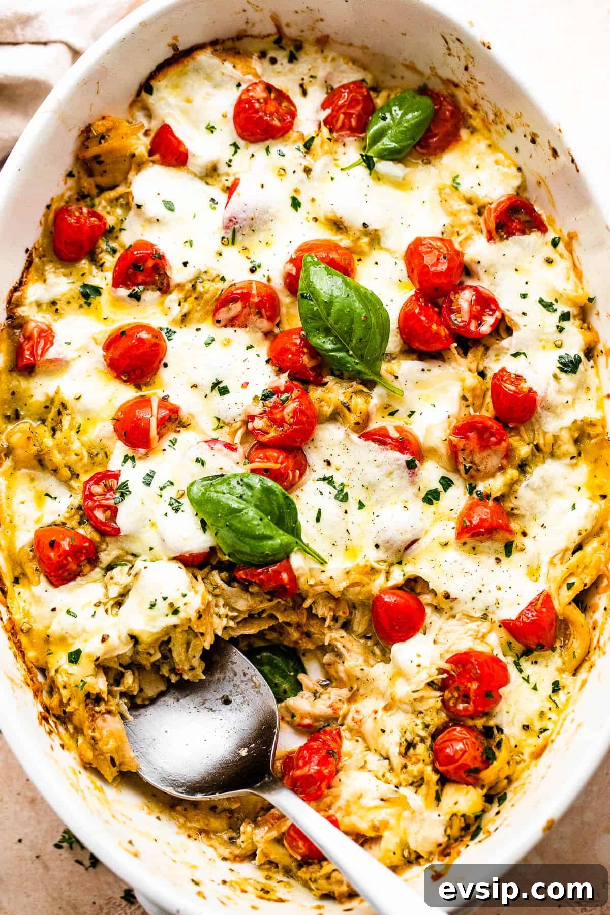 spooning out chicken caprese casserole from the baking dish