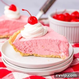 Slice of cherry cool aid pie on white plate with large glass of milk in the background.