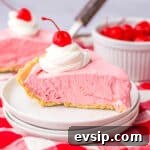 Slice of cherry cool aid pie on white plate with large glass of milk in the background.