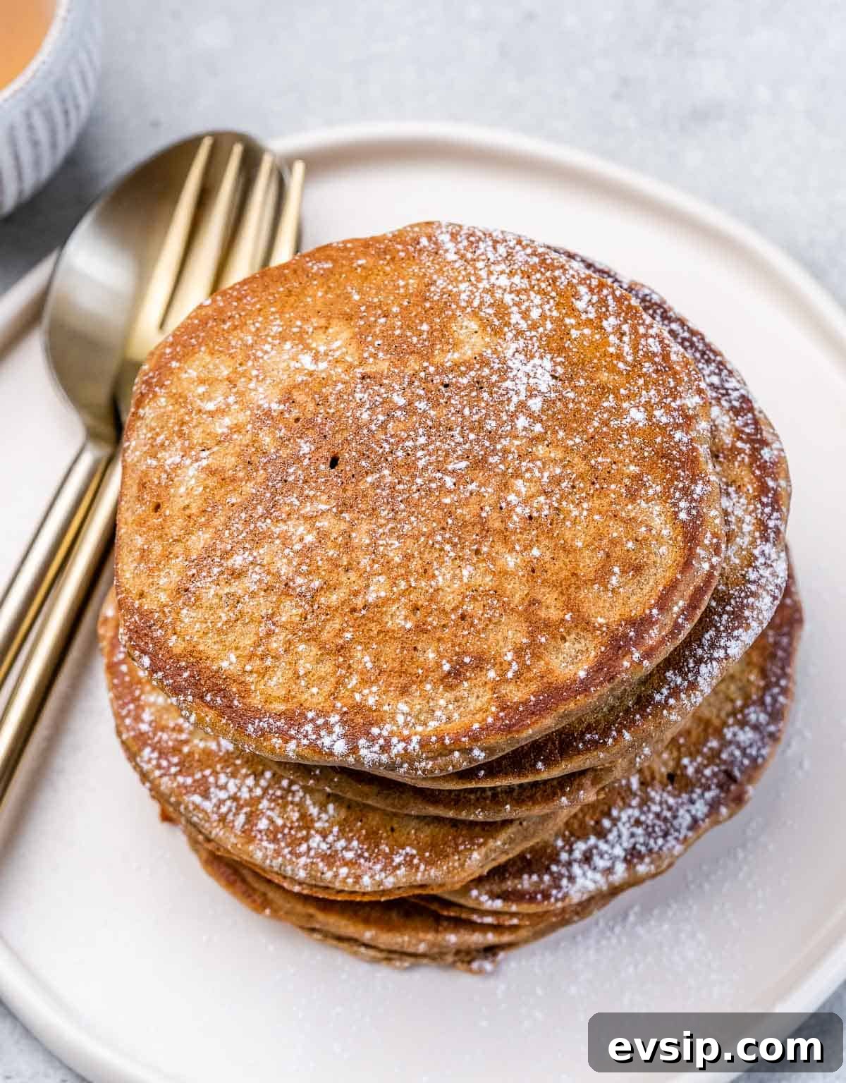 Top view of a stack of pancakes dusted with powdered sugar.