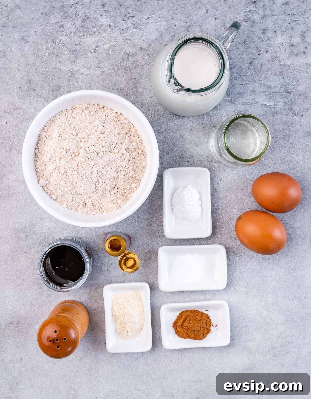 Flour in a bowl near eggs spices, oil and milk.