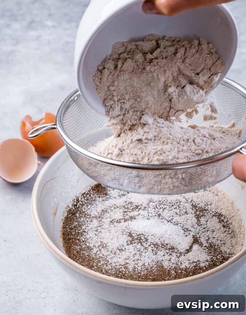 Sifting flour over egg mixture in a bowl.