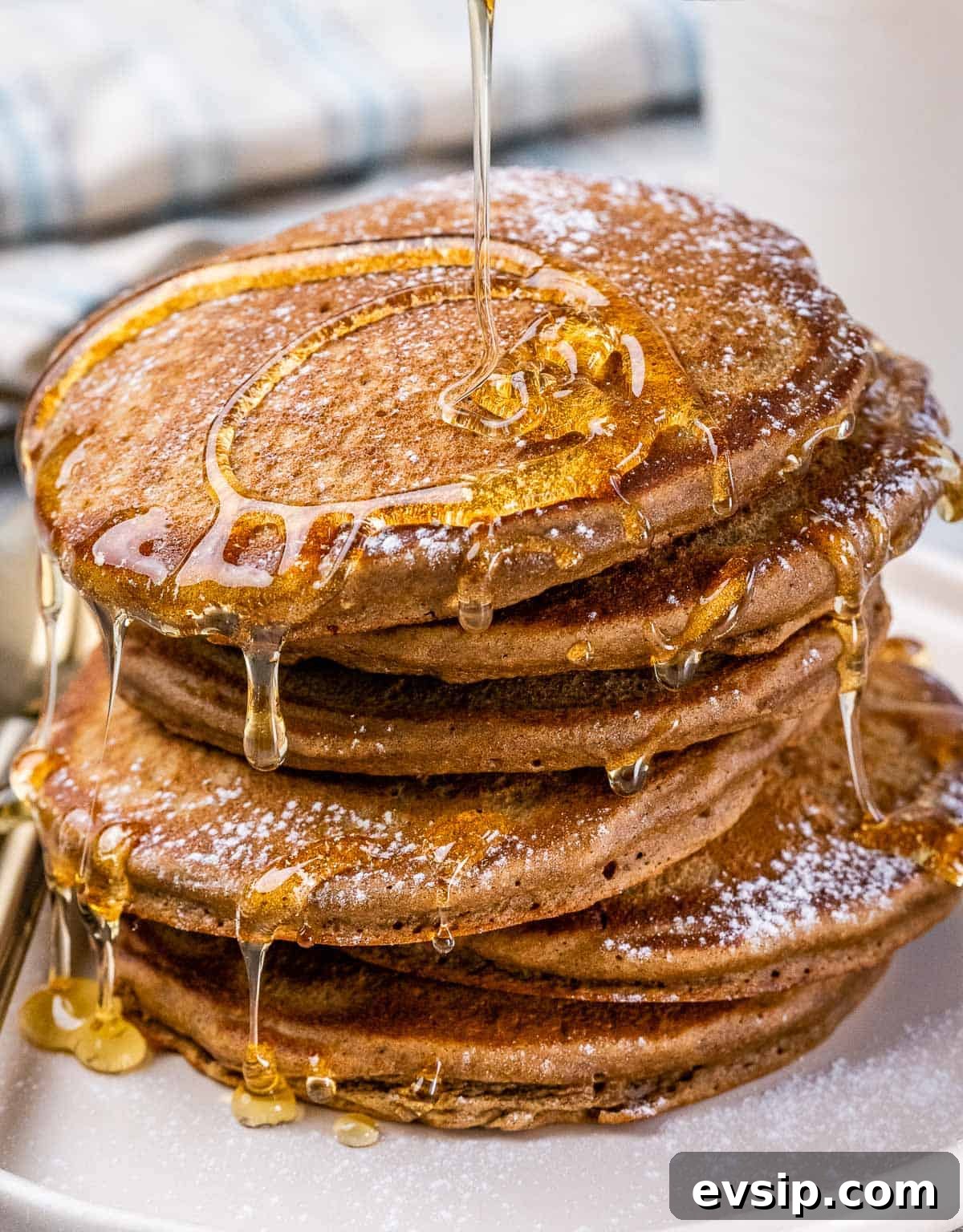 Closeup view of a stack of pancakes drizzled in maple syrup.