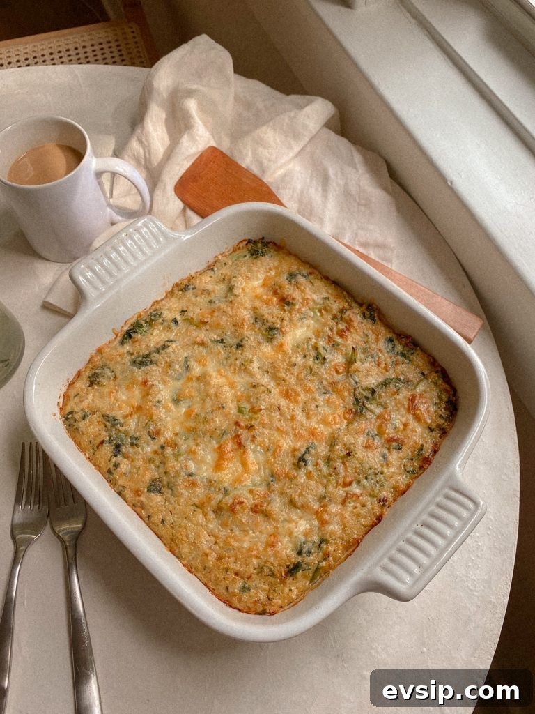 broccoli cheddar quinoa breakfast bake in a white baking dish with a wooden spoon and mug of coffee