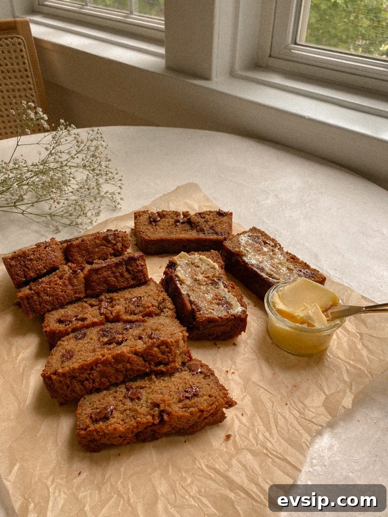 zucchini bread slices on brown parchment paper with small bowl of butter and white flowers