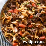 Beef and noodles cooked in a dish with carrots and peas