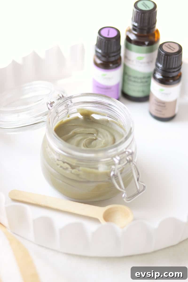 a jar of homemade anti-itch cream with essential oils behind it