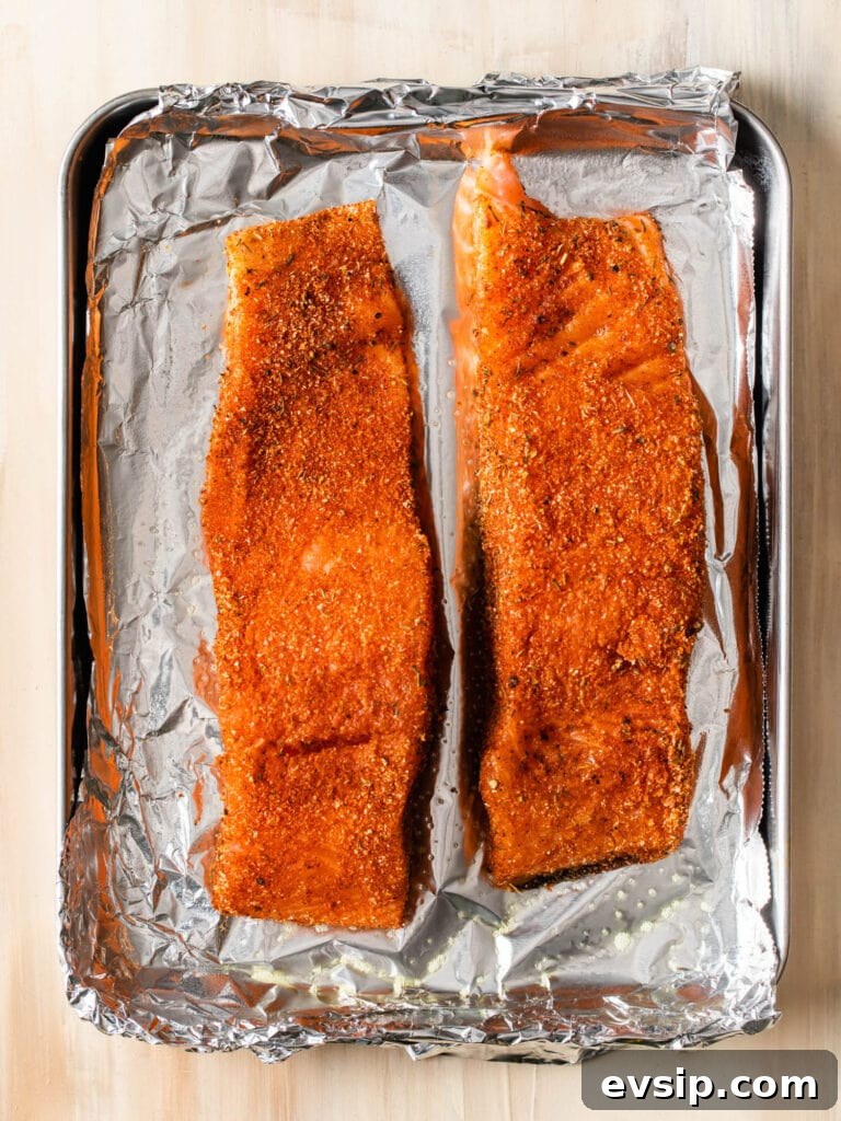 Blackened Baked Salmon with Creamy Cheddar Grits 3 two pieces of salmon seasoned with blackening seasoning on a sheet pan