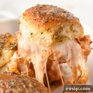 Close up view of chicken parmesan sliders with a cheese pull.