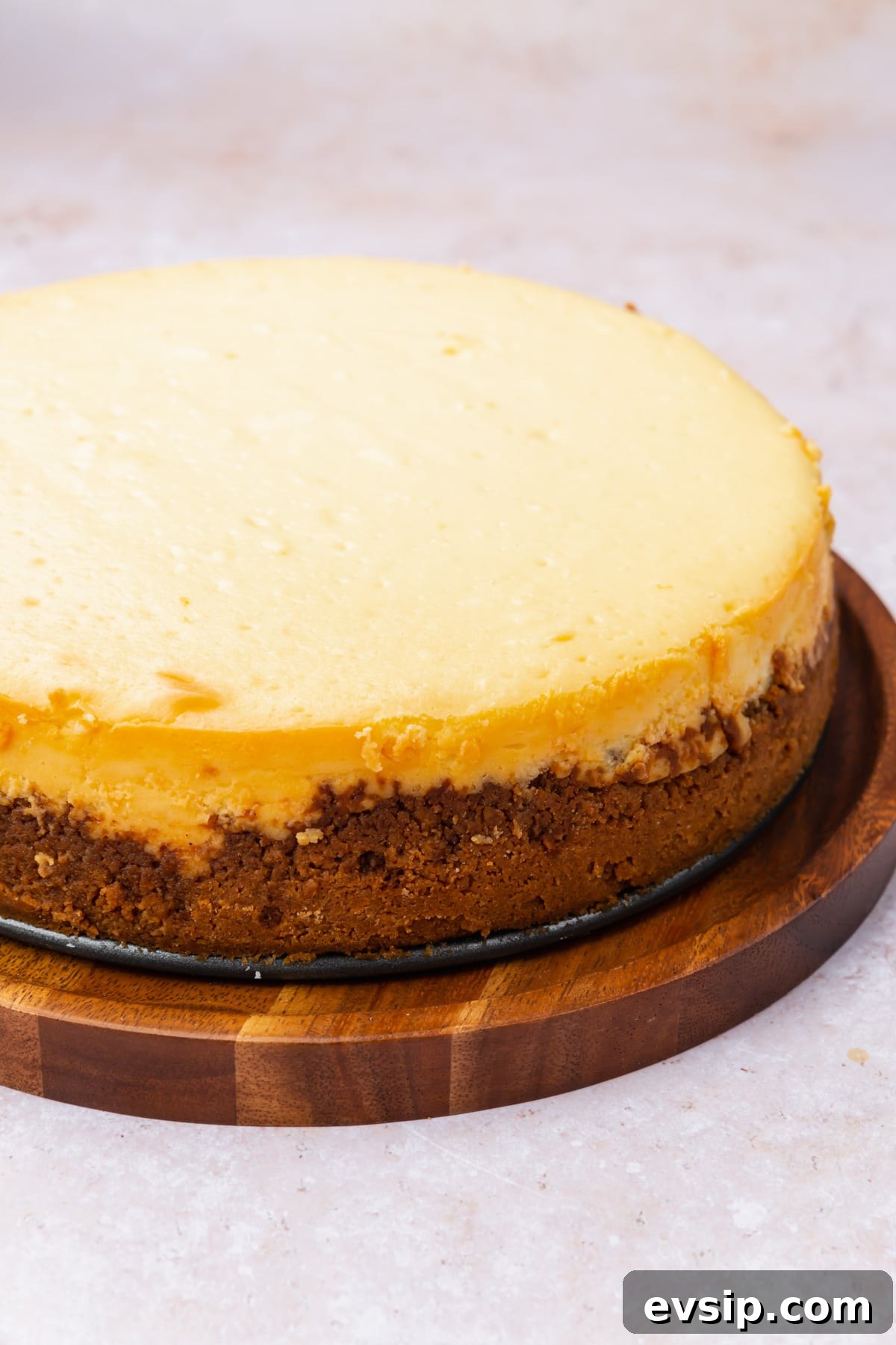 A plain gluten-free cheesecake on a wood board.