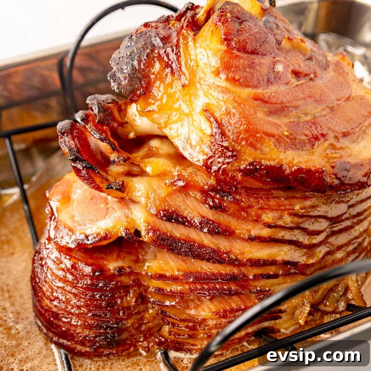 Brown sugar glazed ham on a roasting rack in a pan, with crispy edges and visible caramelization.