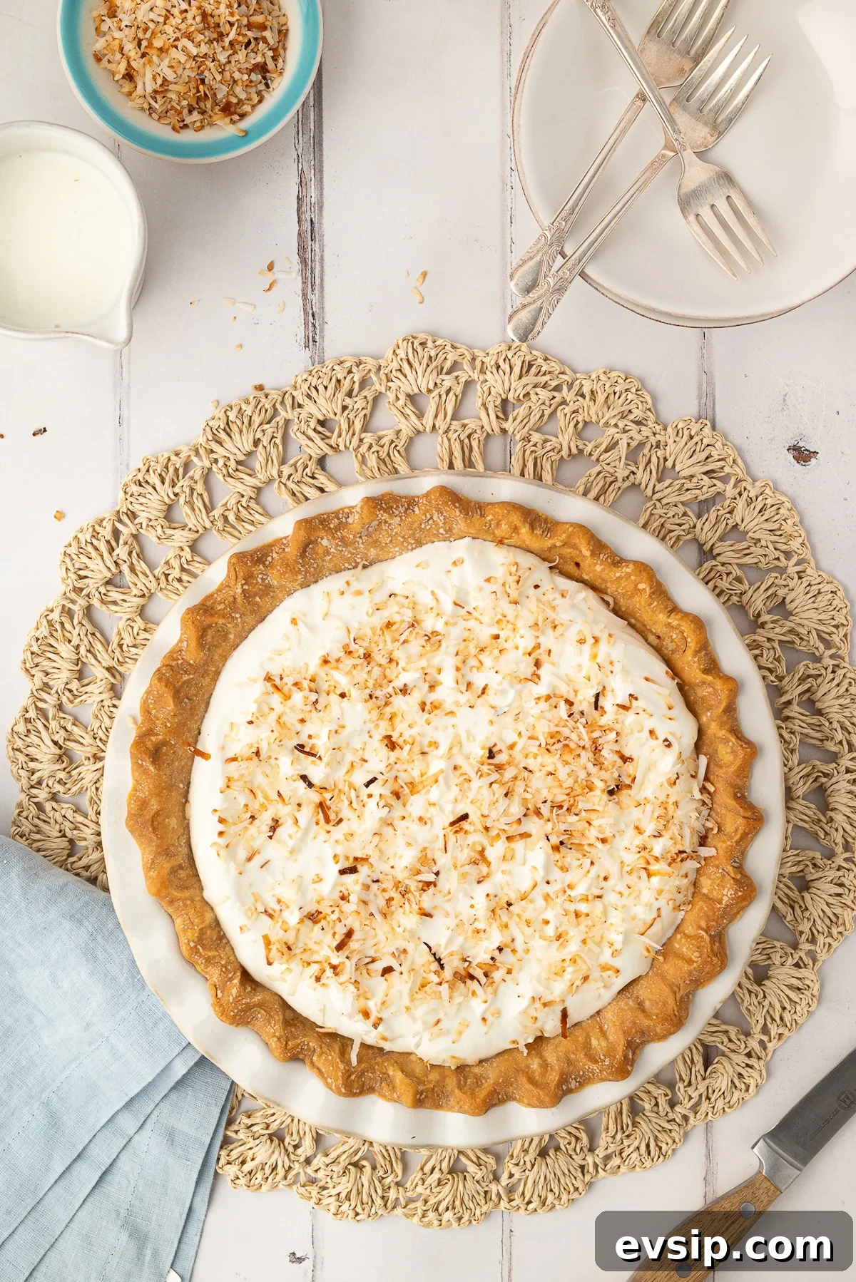 A whole baked coconut pie in a pie dish, finished with a fluffy whipped cream topping and golden toasted coconut. A classic Southern dessert perfect for Easter or any occasion.