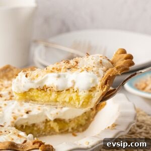 A side view of a slice of easy coconut pie lifted on a pie server, showcasing the baked custard-like pie filling and creamy whipped topping.