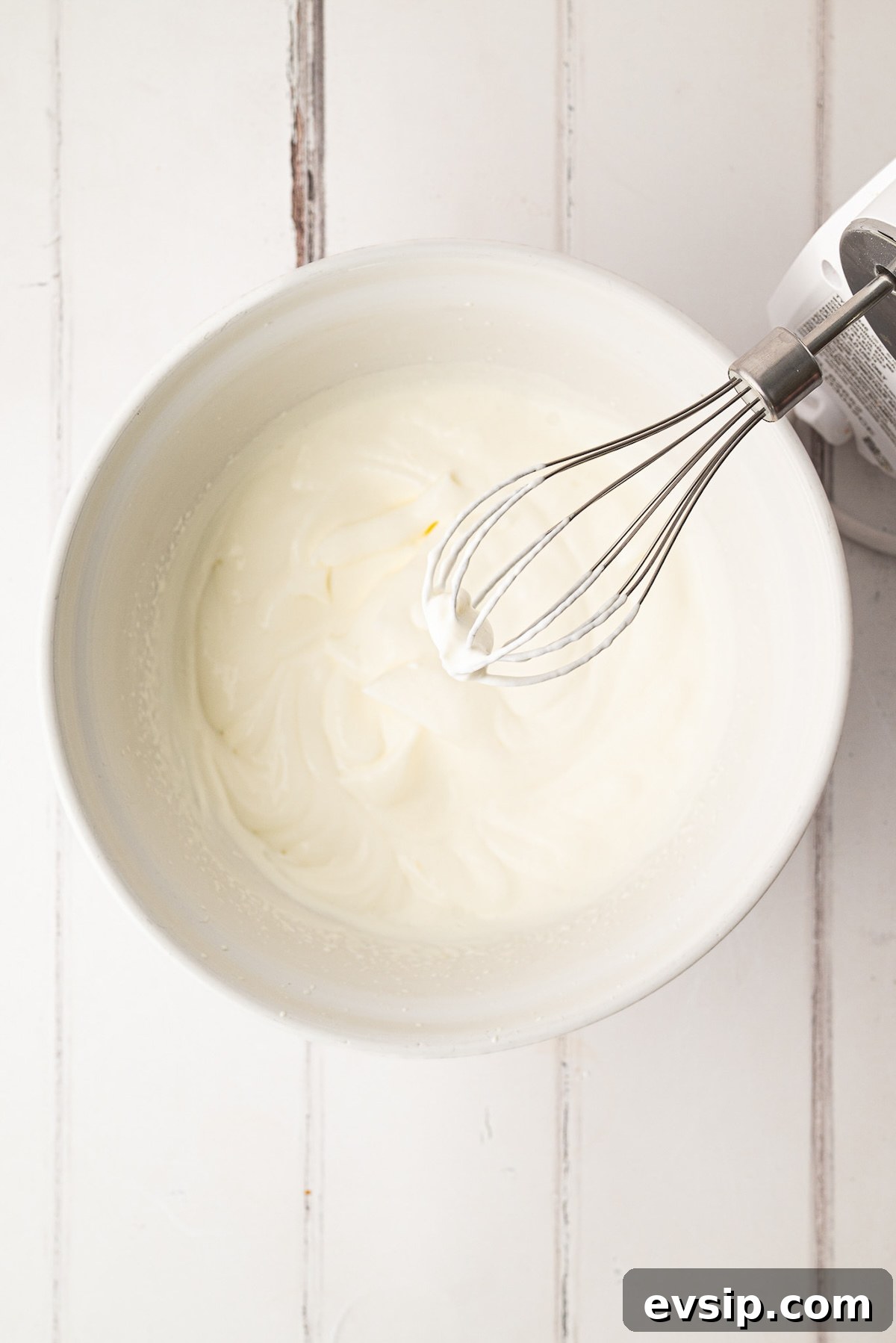 Whipping together powdered sugar and heavy cream to make a lightly sweetened chilled pie topping.