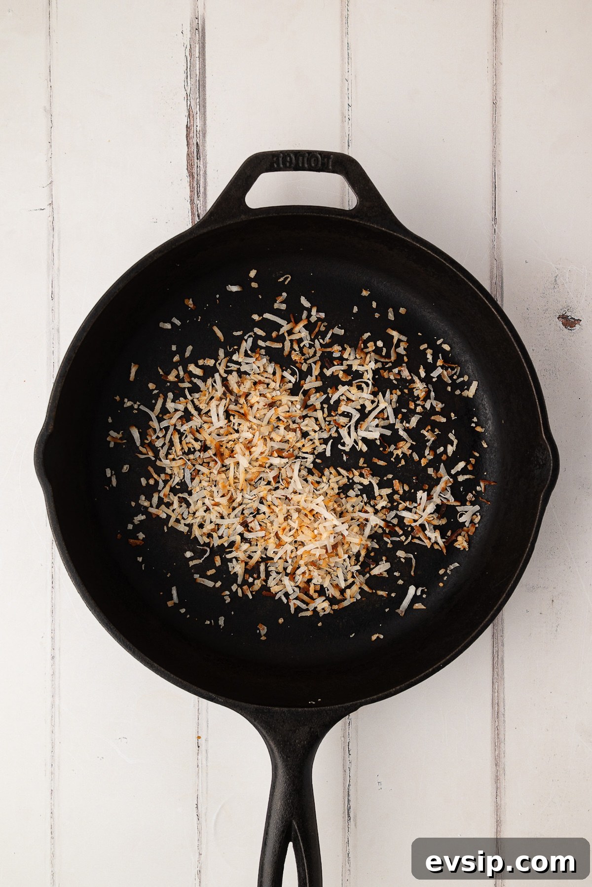 Toasting sweetened shredded coconut flakes in a skillet as a garnish for the whipped cream pie topping.