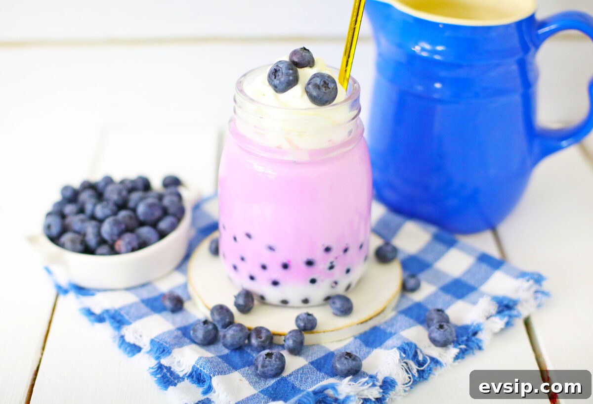 blueberry boba milk tea in glass with gold straw