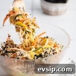 Kani salad on a fork being held over a glass bowl filled with kani salad.