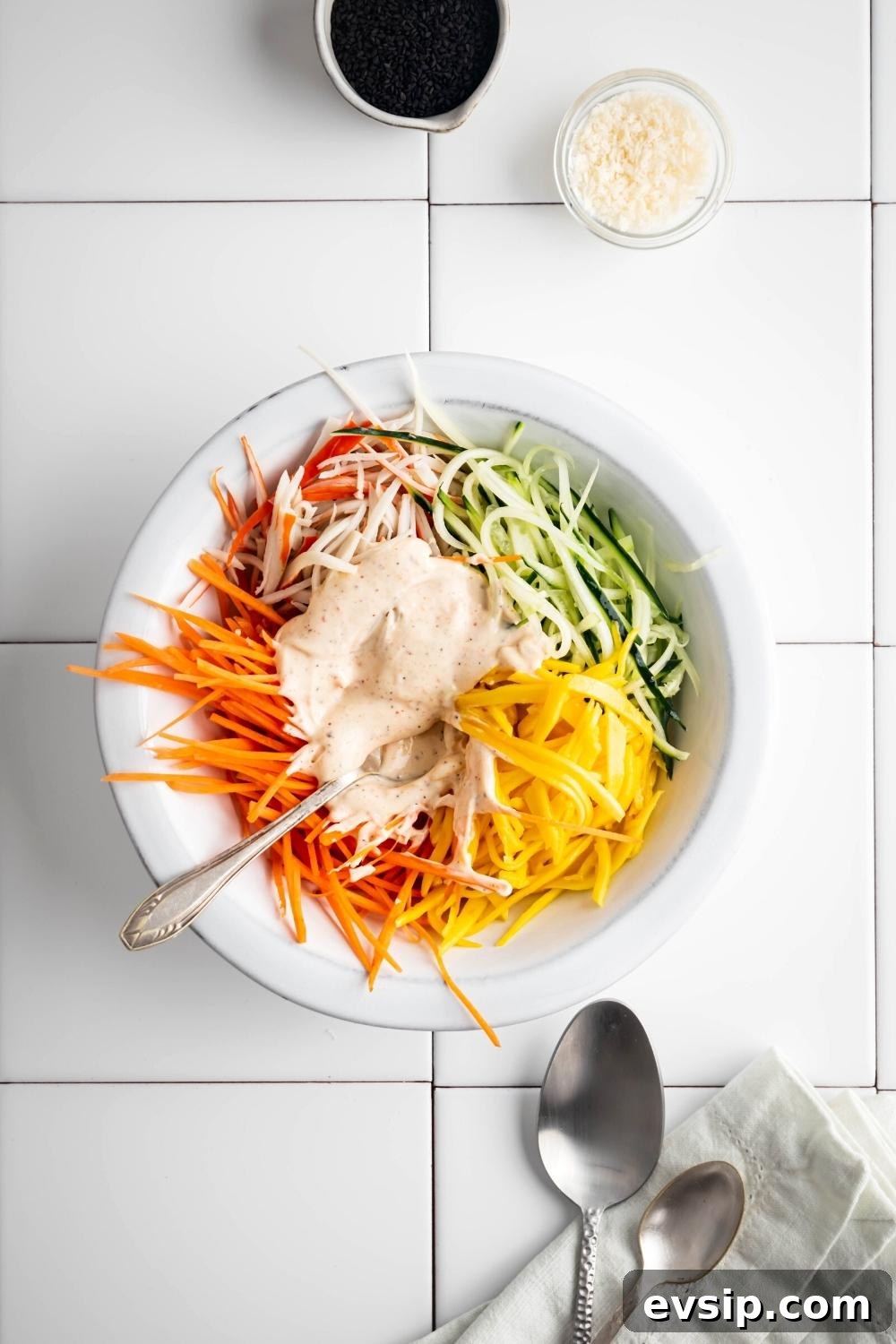 Dressing and julienned ingredients in bowls on a counter.