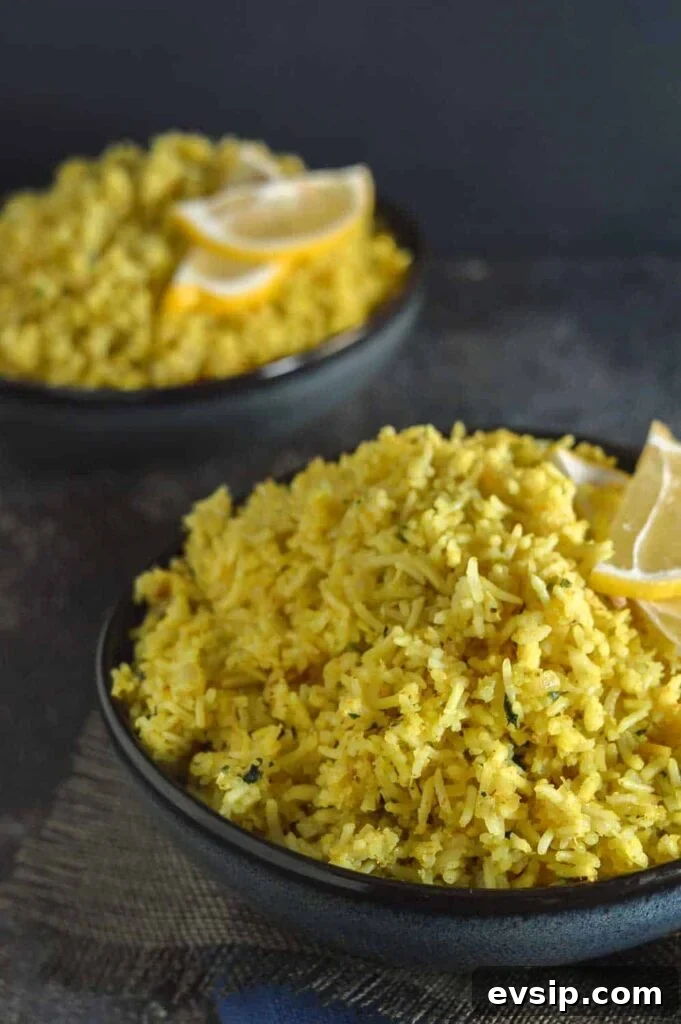 Two navy bowls of yellow rice with lemon slices on top