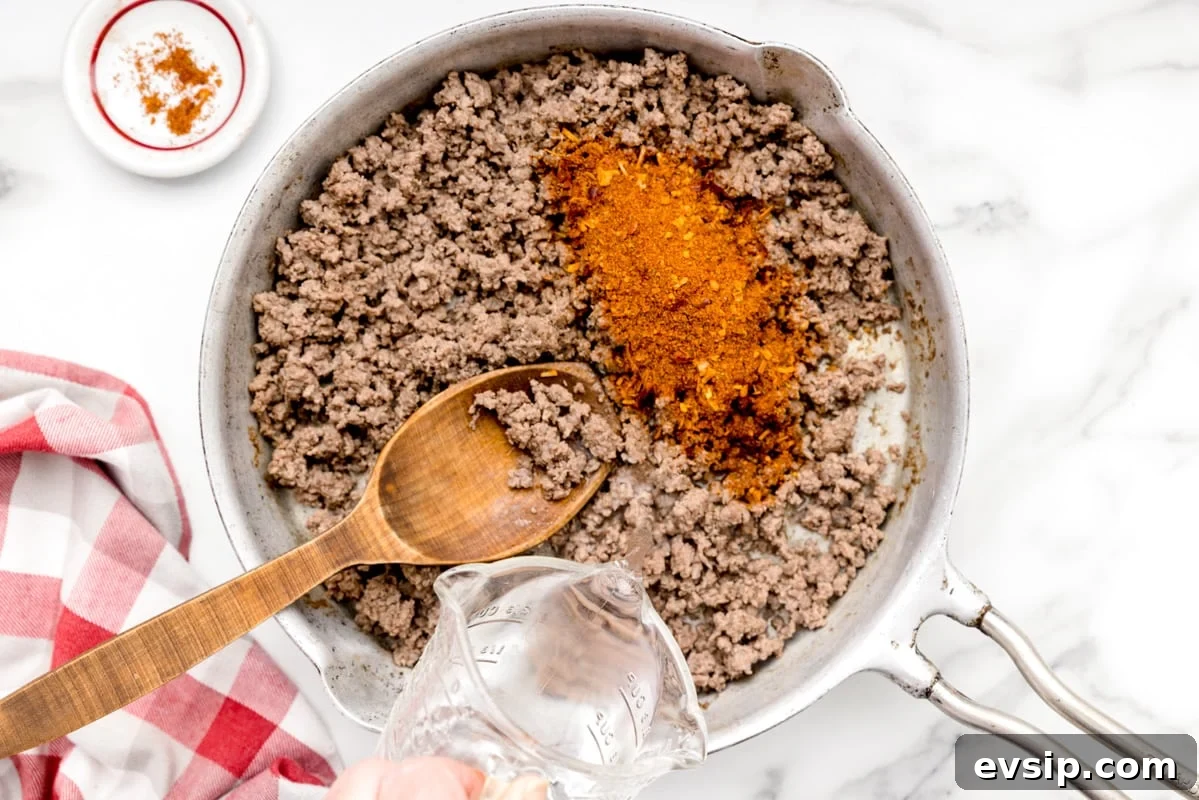 Homemade taco seasoning is simple, made with ingredients that are usually on hand. It gives a delicious flavor to any recipe!! Adding seasoning to a pan of ground beef.