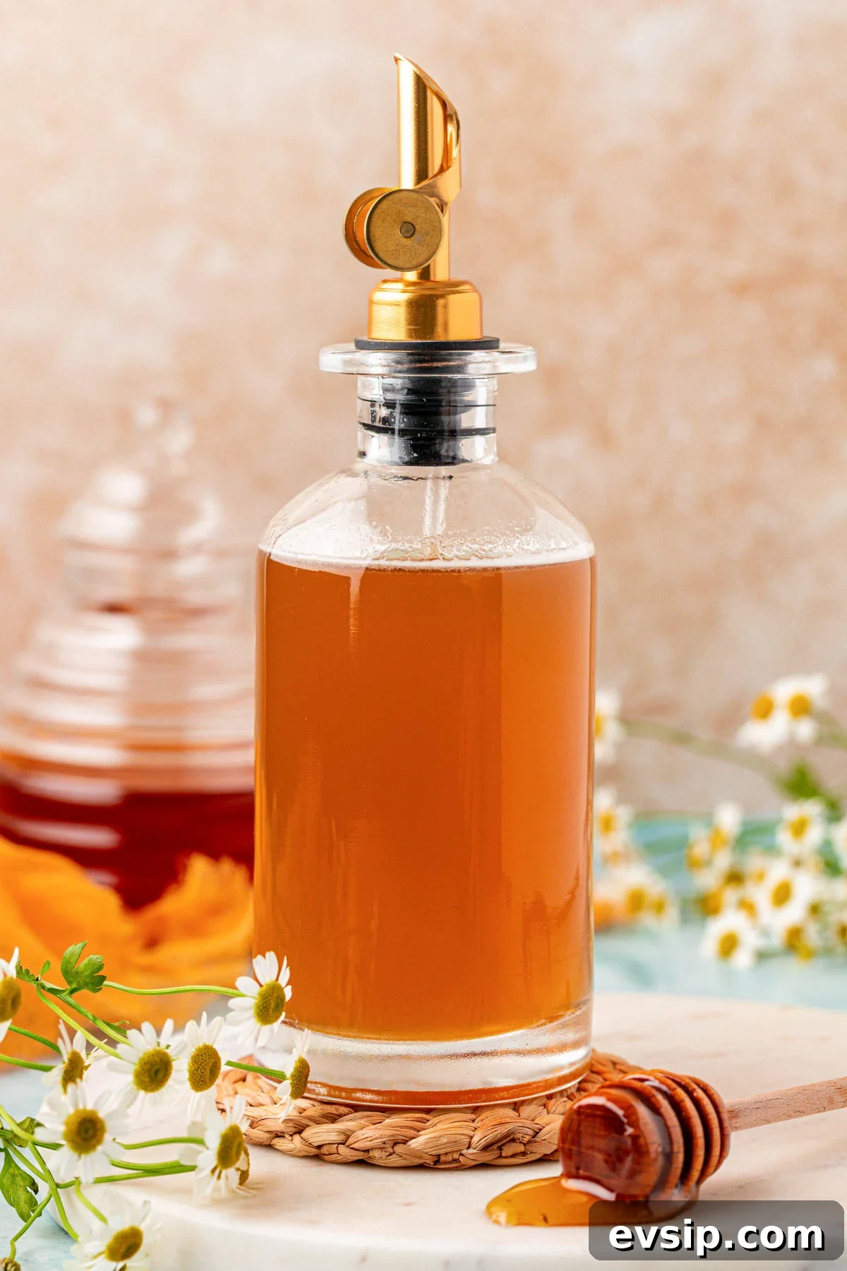 A glass bottle of honey simple syrup on a rope coaster.