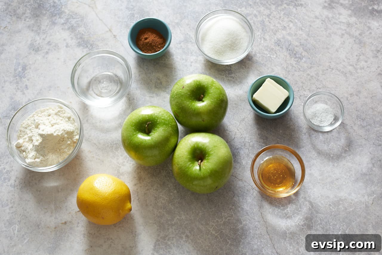 Three granny smith apples, one lemon, and small bowls of flour, water, sugar, salt, honey, butter and cinnamon.