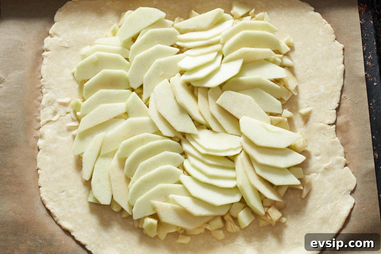 Apple pieces and slices arranged in a design on top of a piece of pastry.